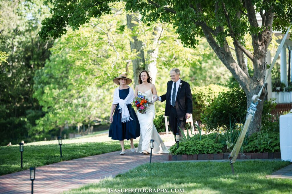 bride walking with parents during wedding ceremony
