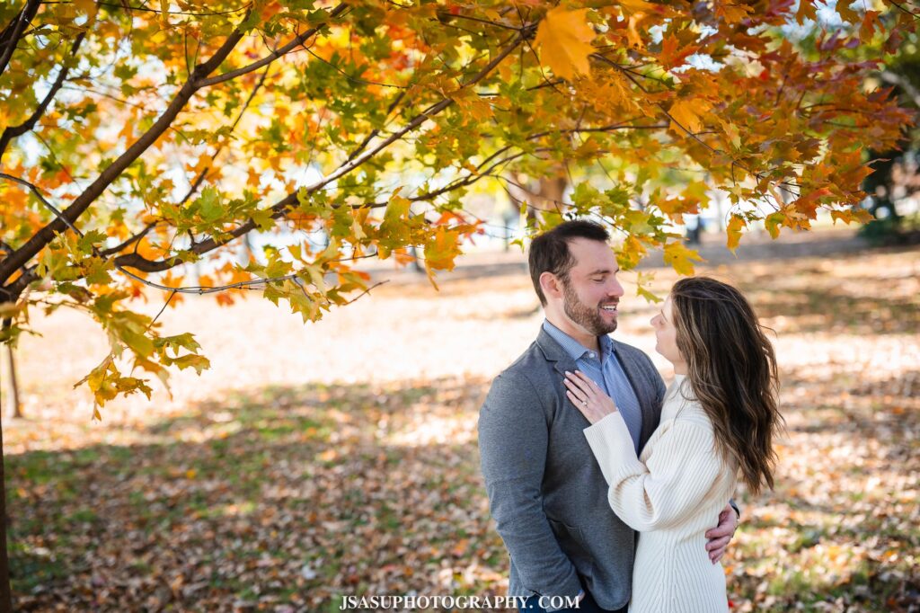 a couple under the autumn leaves during their engagement session at the national mall