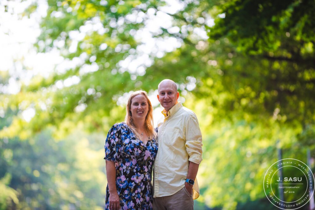 a couple stands with trees in the background as they pose for photos in Gaithersburg, Maryland