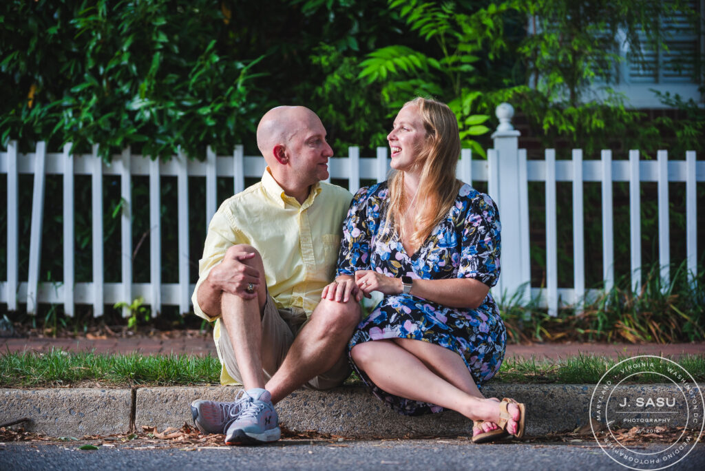 a couple sitting laughs during their engagement session in the Kentlands in Gaithersburg, MD. 