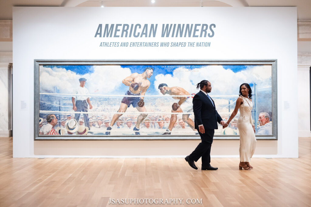 Couple walks past American Winners portrait at the National Gallery of Art in Washington, DC