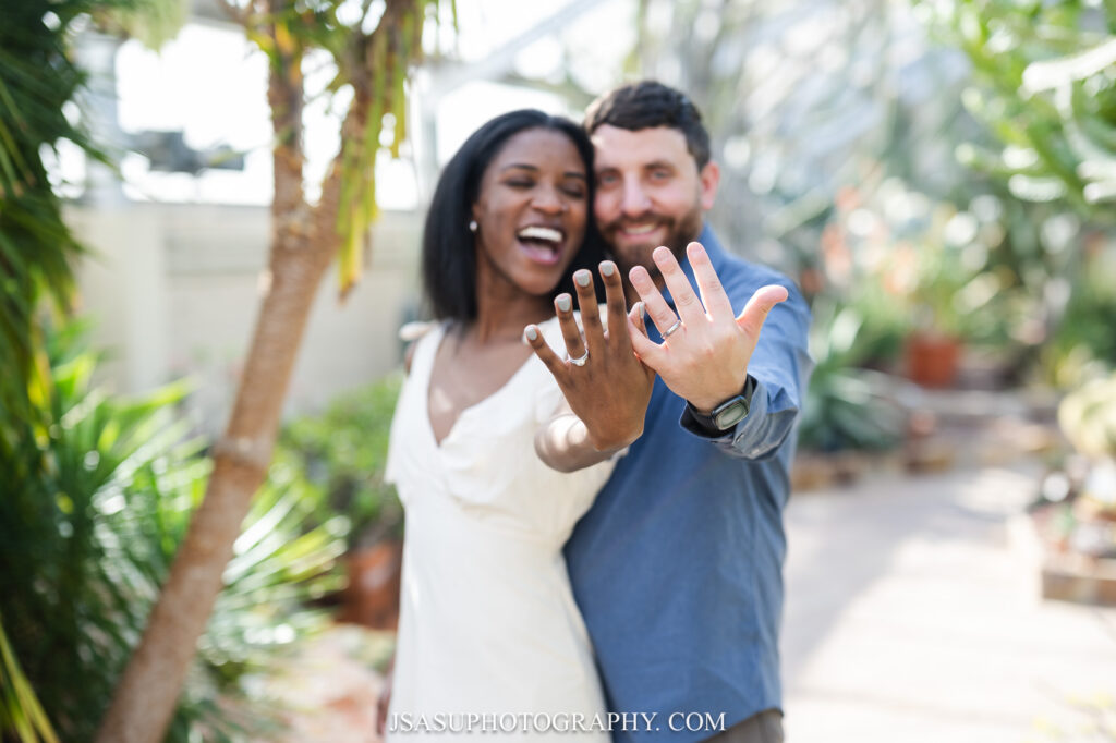 a man and woman show their new weddings bands at Rawlings Conservatory in Baltimore, MD 