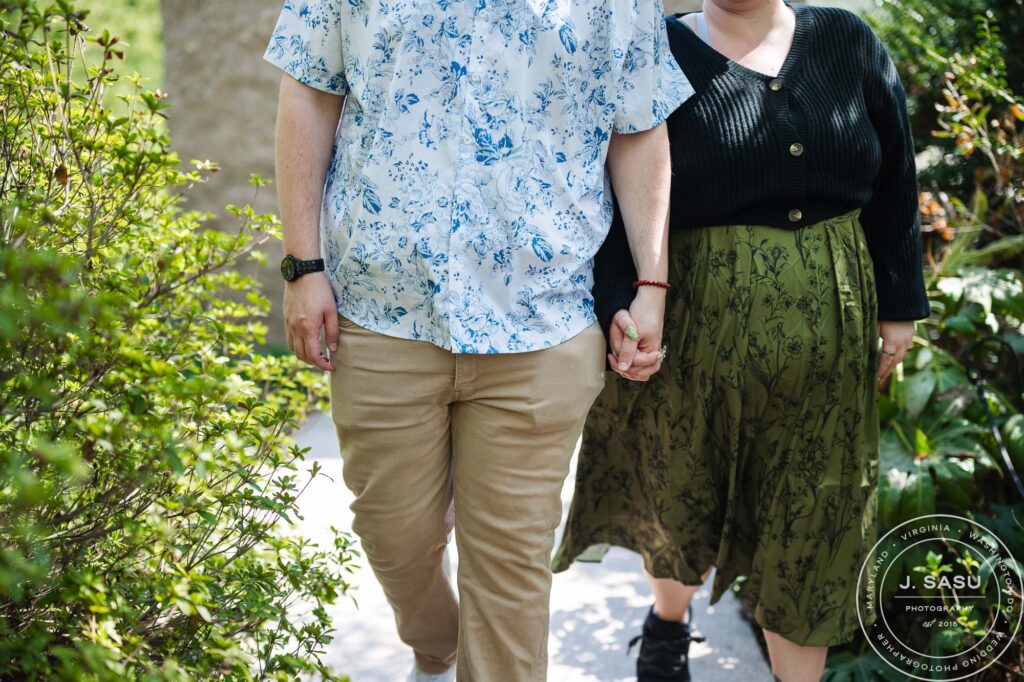 A couple holding hands walks through the Moongate Garden in Washington, DC after their engagement. 