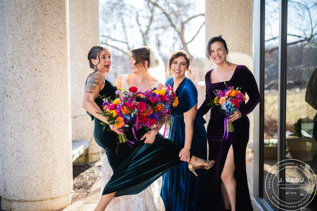 a bride and her bridesmaids have a candid photo taken on wedding day at the atrium at meadowlark botanical gardens