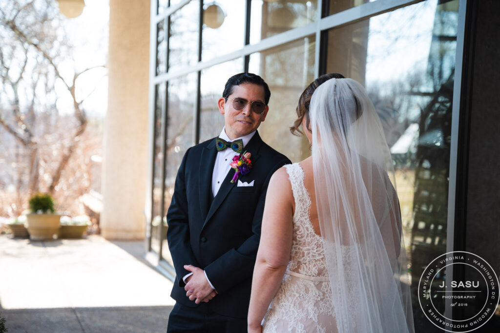 a man in a tuxedo turns to look at his bride for the first time on wedding day at the atrium at meadowlark botanical gardens
