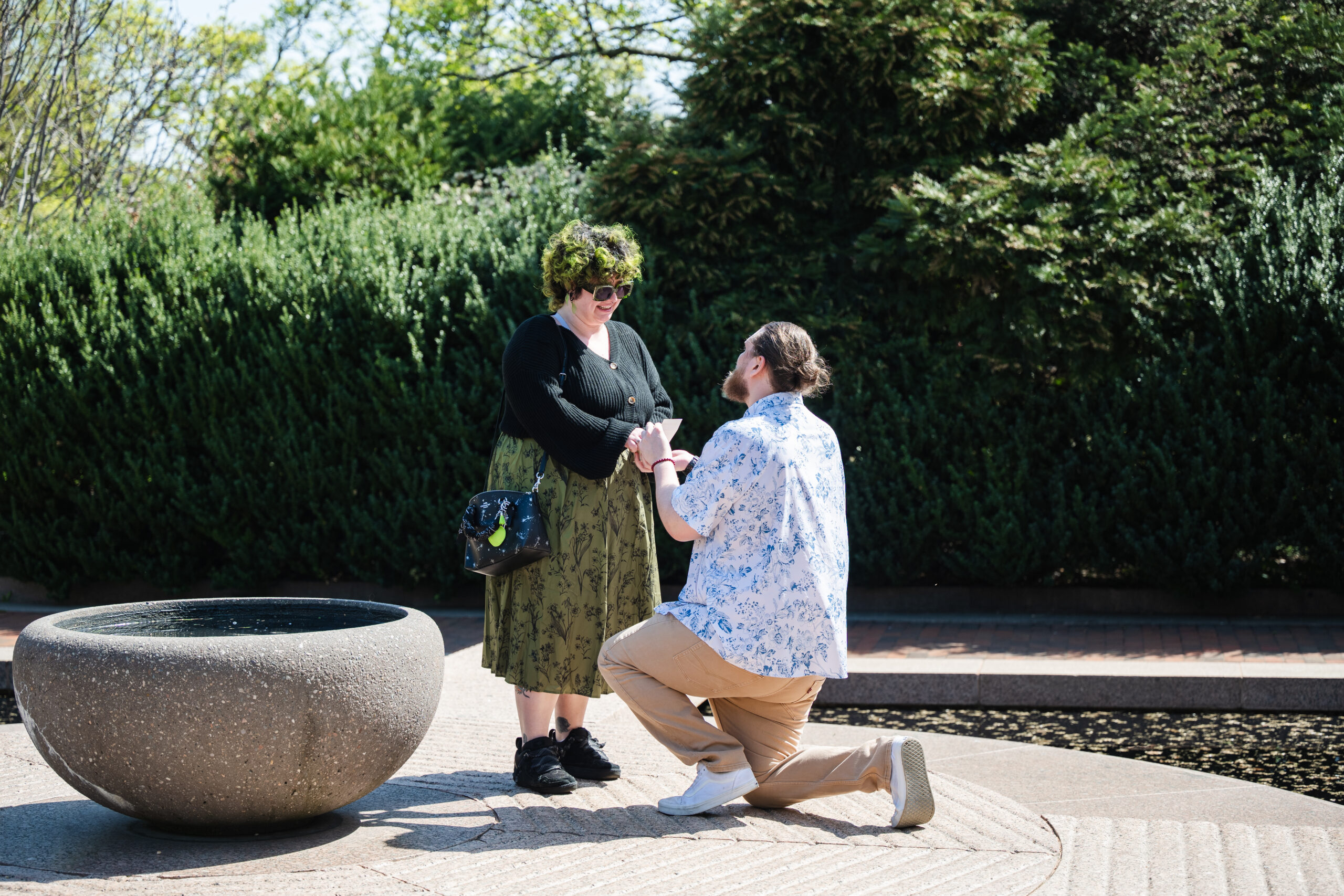 A man gets down on a knee to propose to a woman at the Moongate Garden at Smithsonian Castle in Washington, DC